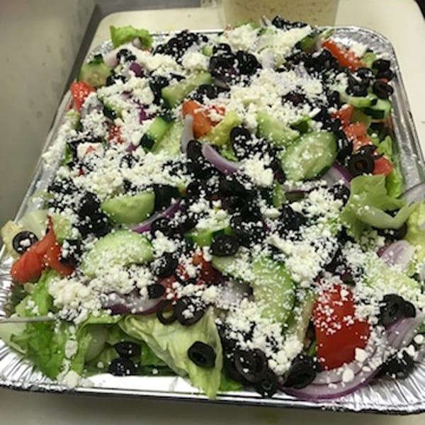 Large deli salad with lettuce, tomatoes, cucumbers, black olives, red onions, and feta cheese.