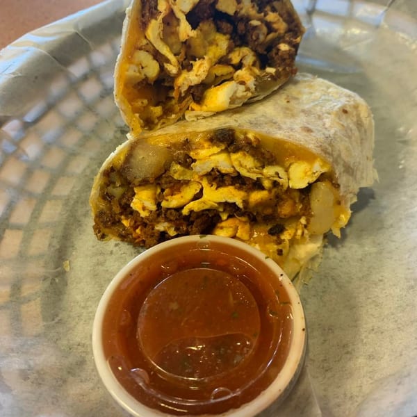 A breakfast burrito from Rinaldi's Italian Deli, cut in half, with a side of salsa.