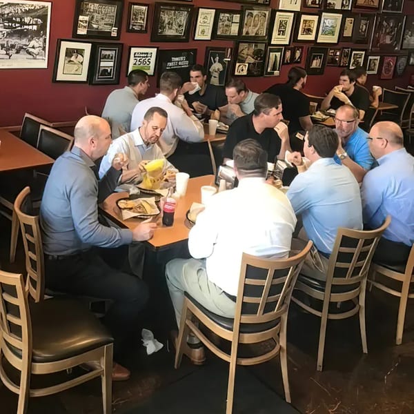 Customers enjoying sandwiches and drinks at Rinaldi's Italian Deli, surrounded by framed photos.
